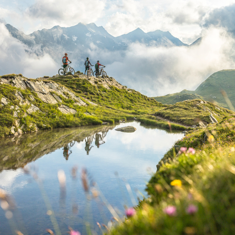 Mountainbiker mit Blick auf die Berge bei einem Bergsee in Disentis Sedrun