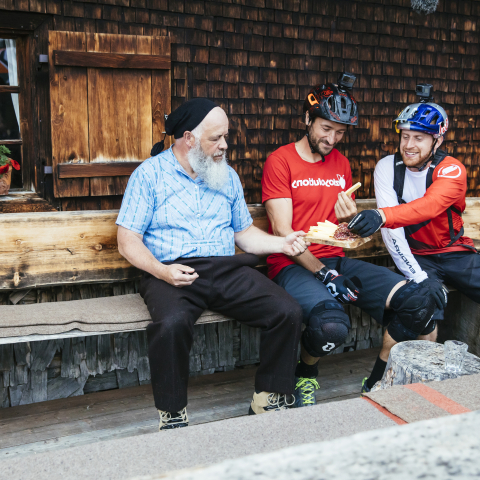 Pause machen bei der Alphütte Fops: Danny MacAskill und Claudio Caluori stärken sich mit einem Bündner-Plättli (Bild: Martin Bissig) Pause machen bei der Alphütte Fops: Danny MacAskill und Claudio Caluori stärken sich mit einem Bündner-Plättli (Bild: Martin Bissig)