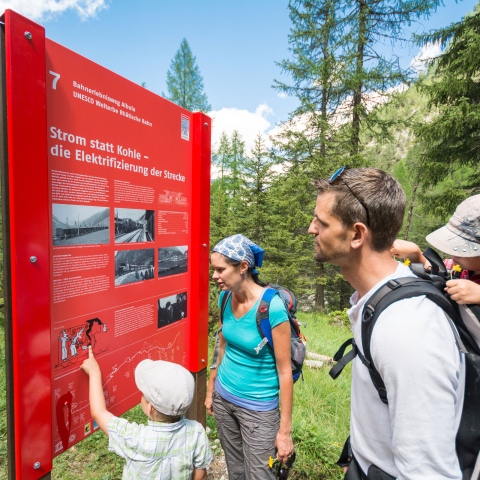 Découvrez l'interaction parfaite entre le paysage et la technologie sur le chemin de fer de l'Albula (Photo : © Chemin de fer rhétique / Mattias Nutt) Une famille étudie un tableau sur le parcours d'aventure du chemin de fer de l'Albula
