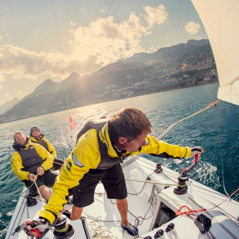 Im Engadin trifft sich regelmässig die internationale Elite der Segelwelt (Foto: © Engadin Tourismus AG / Filip Zuan) Drei Männer mit Schwimmwesten auf einem Segelboot auf dem St. Moritzersee