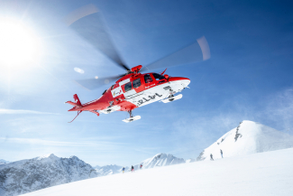 Ein Rettungshelikopter der Rega auf dem Weg zur Einsatzstelle (Foto: © Rega / Andrea Badrutt) Ein Rettungshelikopter der Rega im Anflug auf eine Skipiste