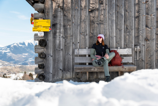 Person sitzend vor einem Stall auf der Via Mundaun vor Curschella