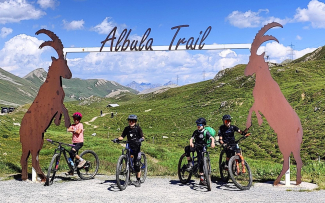 Startklar auf dem Albula Trail Junge Biker unter dem Albula-Trail-Tor mit Steinböcken