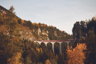 Landwasserviadukt mit der RhB im Herbst (Foto: © Giglio Pasqua) Das Landwasserviadukt umgeben von Baumen in der Herbstpracht und darüber fährt die Rhätische Bahn.