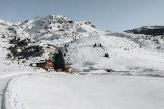 Winterliches Berghaus Piz Platta im Val Surses, umgeben von verschneiten Hängen und Bergen.