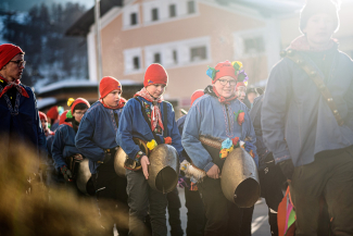 Children in blue smocks and red hats with large cowbells during the traditional Chalandamarz parade in Zernez