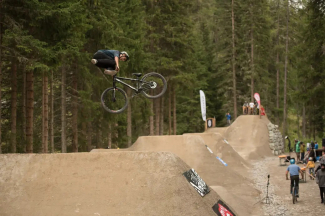 Ein Dirtbiker springt mit seinem Spezialrad über einen Erdhügel auf der Dirtline im Bikepark Färich in Davos