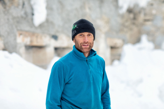 Portrait of Mario Riatsch in a blue fleece jacket and beanie in a snowy winter landscape