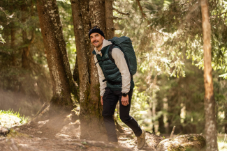 Nino Schurter der Fairtrail Botschafter wandert in Outdoor-Kleidung durch den Wald.