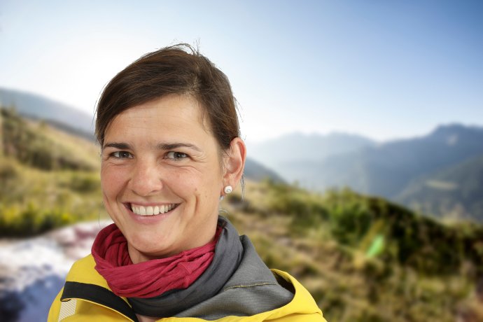 Porträt von Wanderleiterin Susanne Kern vor einer verschwommenen Berglandschaft