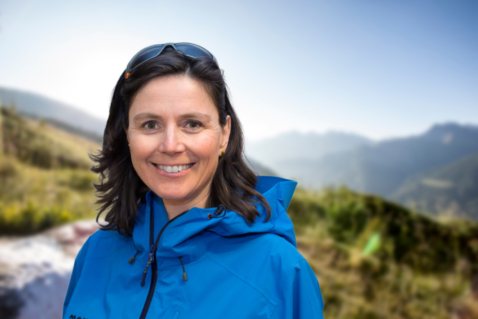 Porträt von Anita Panzer in blauer Outdoorjacke mit Alpenhintergrund