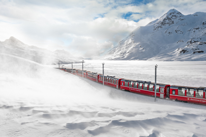 The Bernina Express travels through a snow-covered landscape at Lago Bianco