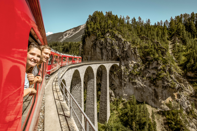 Ein Zug der Rhätischen Bahn auf dem Landwasserviadukt (Foto: © Schweiz Tourismus / Rob Lewis Photography) Ein Paar geniesst den Ausblick aus einem Zug der Rhätischen Bahn auf dem Landwasserviadukt