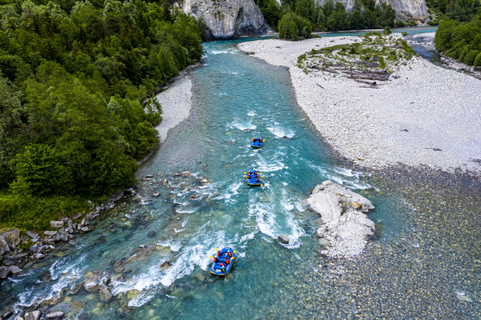Drei Schlauchboote fahren die Rheinschlucht hinunter