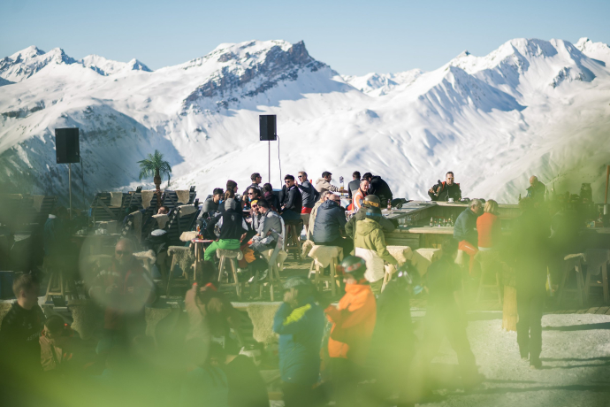 Sonnenterrasse auf der Jatzhütte in Davos (Foto: © Marco Hartmann, Graubünden Ferien) Menschen tanzen und feiern auf der Sonnenterrasse der Jatzhütte in Davos, umgeben von verschneiten Alpen