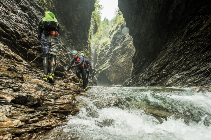 Beim Canyoning ist das Abtauchen in die verborgene Viamala-Schlucht besonders eindrücklich (Foto: © Schweiz Tourismus / Ivo Scholz) Drei Personen in Neoprenanzügen stehen am Rand der Viamala-Schlucht und halten sich an einem Seil fest