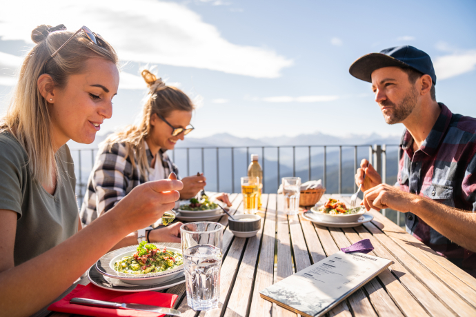 Wander*innen geniessen Mahlzeit und Aussicht in Flims (Foto: © Flims Laax Falera) Wander*innen geniessen Mahlzeit und Aussicht in Flims