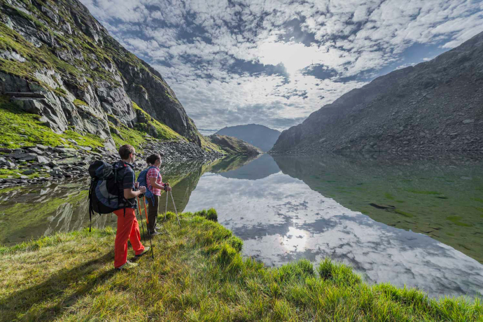 Der Tomasee liegt in einem Kessel am Fusse des Piz Badus (Foto: © Sedrun Disentis Tourismus SA / Mattias Nutt) Ein Paar steht am Tomasee und blickt in die Ferne