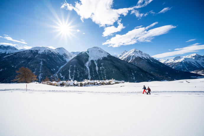 Zwei Wandernde unterwegs auf dem Winterwanderweg Via Engiadina oberhalb von Guara