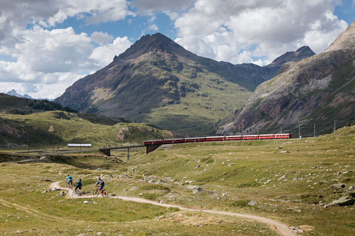 Bernina Express (Foto: © Filip Zuan) Mountainbiker fahren entlang der Bahnlinie mit dem Bernina Express