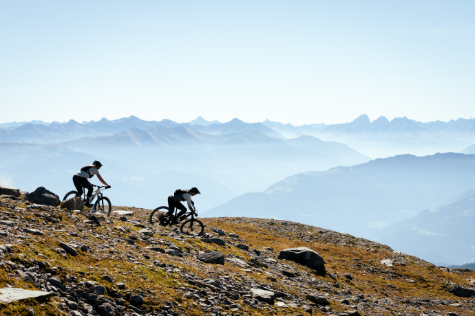 Zwei Mountainbiker*innen in Laax mit Aussicht auf die Berge