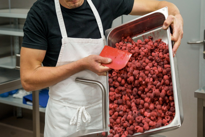 Die Himbeeren werden auf ihre Qualität geprüft, bevor sie in die Rührmaschine gelassen werden (Foto: © Schweiz Tourismus / André Meier) Frische Himbeeren werden in eine Rührmaschine geleert