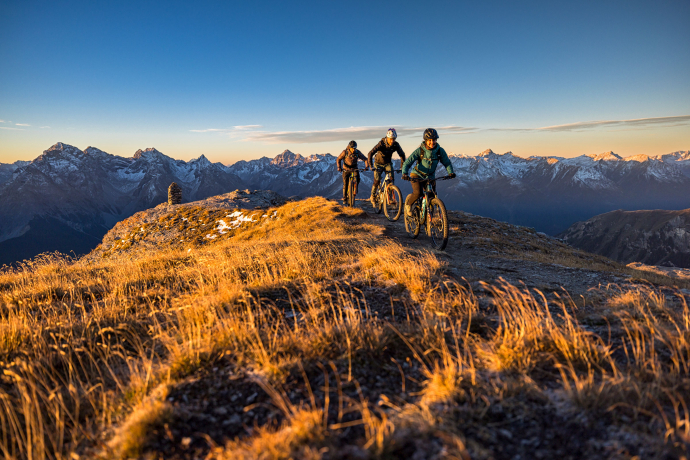 Biker*innen unterwegs bei Sonnenaufgang im herbstlichen Graubünden