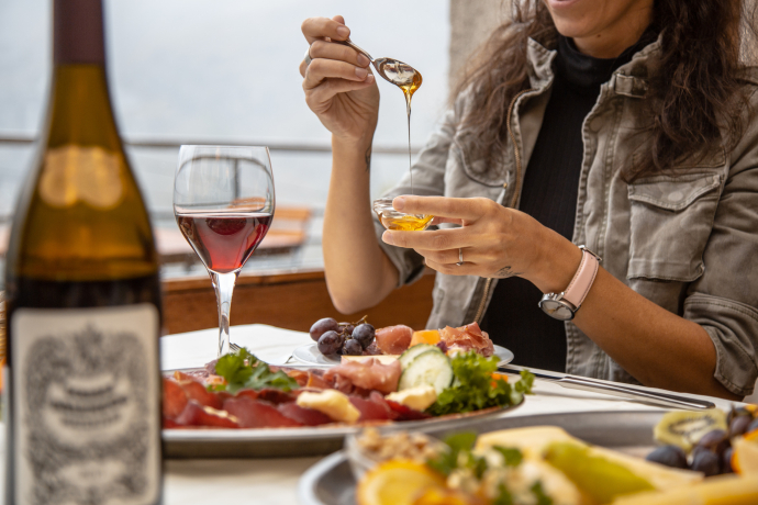 Kulinarischer Zwischenstopp auf der Alp Grüm beim Berninapass (Foto: © Schweiz Tourismus / Francesco Baj) Eine Frau nimmt auf der Terrasse des Restaurant Alp Grüm etwas Honig aus eine Glas