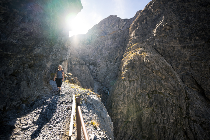 Wanderin auf dem Felsenweg Val d'Uina mit Morgensonne am wandern.