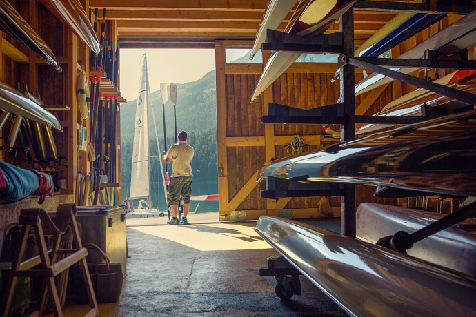 Das Bootslager ist bereit für die Wasserfans (Foto: © Engadin Tourismus AG / Filip Zuan) Ein Mann mit zwei Paddeln in den Händen steht in einem Bootslager im Engadin