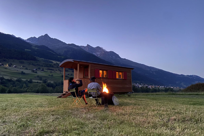 Zwei Personen sitzen beim Lagerfeuer auf dem Stellplatz in Surrein