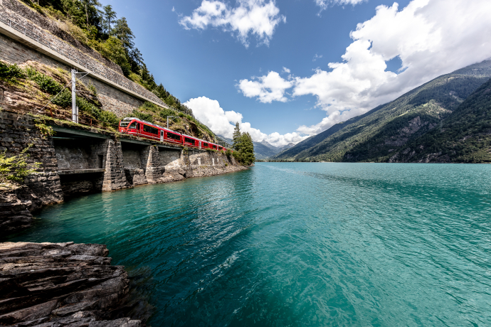 Il Lago di Poschiavo è un bacino naturale al centro del fiume Poschiavino (Foto: © Ferrovia retica / Andrea Badrutt) Un treno regionale della Ferrovia Retica corre lungo il Lago di Poschiavo