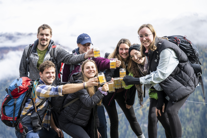Eine Gruppe junger Menschen stösst am Bergbierfestival Tschlin zusammen an