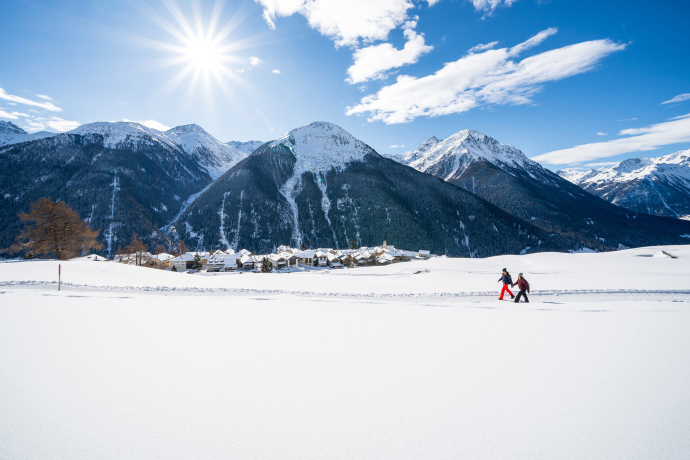 Zwei Wandernde unterwegs auf dem Winterwanderweg Via Engiadina oberhalb von Guarda