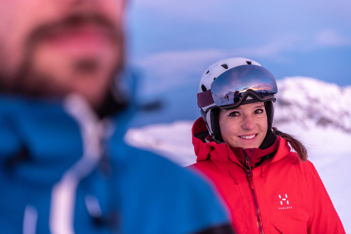 Ein junges Paar auf einer Skipiste in Savognin, die Frau schaut den Mann verliebt an