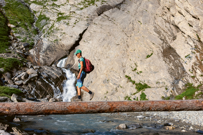Escursionista che cammina su un tronco d'albero nell'Arena tettonica di Sardona.