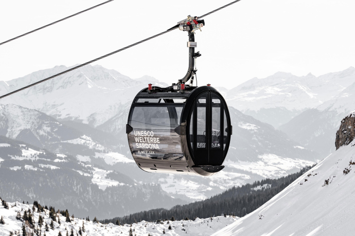 Moderne Gondel schwebt über verschneiter Alpenlandschaft im UNESCO-Welterbe Sardona
