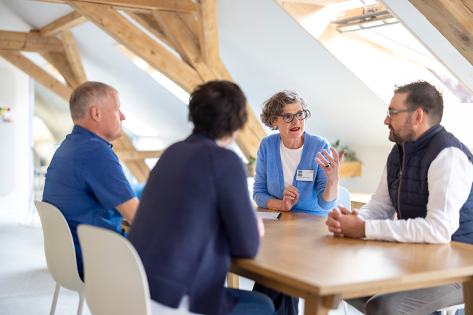 Eine Gruppe von Menschen sitzt an einem Tisch und redet miteinander