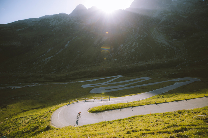 Rennradfahrer in einer Haarnadelkurve auf der autofreien Passstrasse am Splügenpass