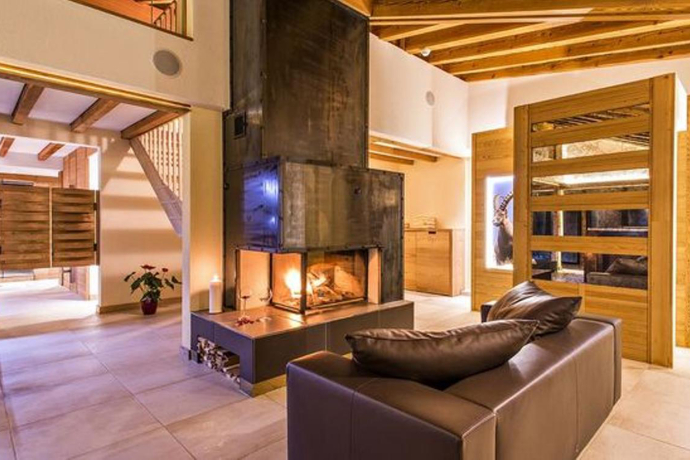 Gemütlicher Loungebereich im Hotel Palü, Pontresina, mit offenem Kamin, Ledercouch und stilvollen Holzelementen