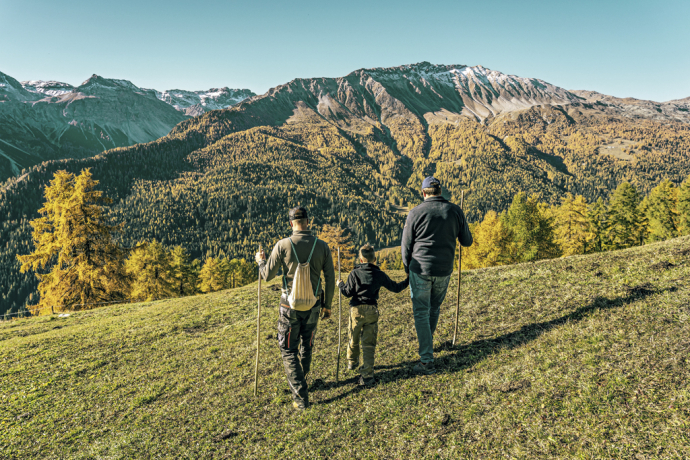Gemeinsam unterwegs: Familienwanderung mit herrlichem Blick über die herbstliche Val Müstair (Foto: © Schweiz Tourismus / Christian Meixner) Zwei Erwachsene und ein Kind wandern mit Aussicht in der Val Müstair