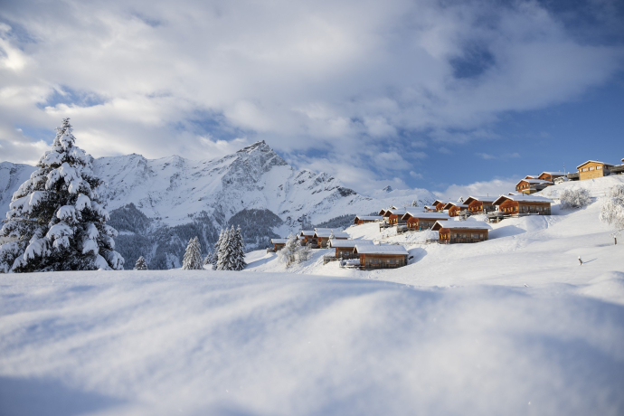 Winteridylle pur im Maiensässresort Aclas Heinzenberg auf dem sonnigen Hochplateau über Thusis (Foto: © Marco Hartmann) Verschneite Holzchalets des Maiensässresorts Aclas Heinzenberg vor winterlicher Bergkulisse