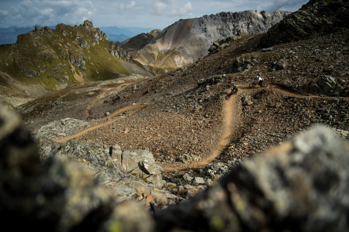 Zwei Mountainbiker fahren auf einem kurvigen Trail durch felsige Berglandschaft im Bike Kingdom Lenzerheide