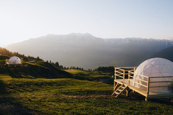 Zwei Glamping-Kuppeln in alpiner Landschaft bei Sonnenuntergang