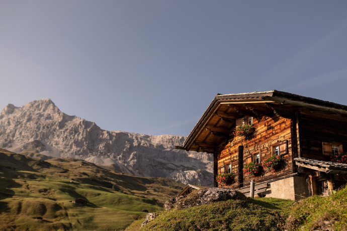 Sonnig beleuchteter Maiensäss mit Blumenschmuck vor Bergkulisse in St. Antönien im Prättigau