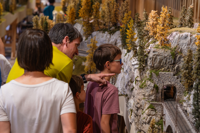 Familie betrachtet eine detailreiche Modelleisenbahnlandschaft im Bahnmuseum Albula