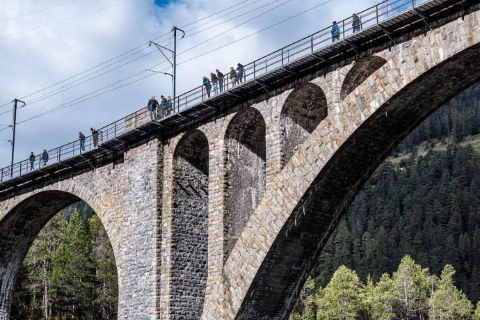 Menschen spazieren auf dem Sky Walk entlang des Wiesnerviadukts inmitten einer bewaldeten Berglandschaft