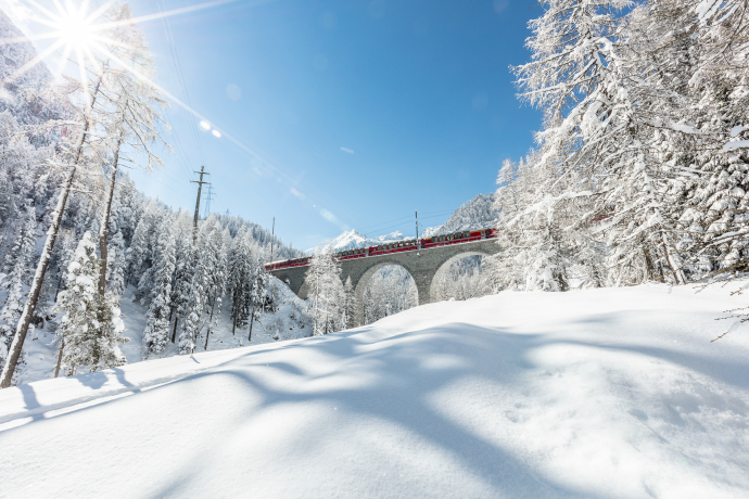Bernina Express auf dem Albulaviadukt in tief verschneiter Winterlandschaft