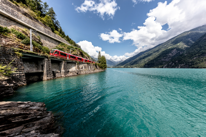 Between water and mountains: the Rhaetian Railway follows the shore of Lago di Poschiavo towards Tirano (Photo: © Rhaetian Railway / Andrea Badrutt) Regional train of the Rhaetian Railway at Lago di Poschiavo on a sunny summer day