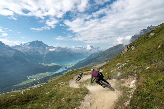 Mountainbiker auf einem Flowtrail mit Blick auf St. Moritz und den Silvaplanersee im Oberengadin